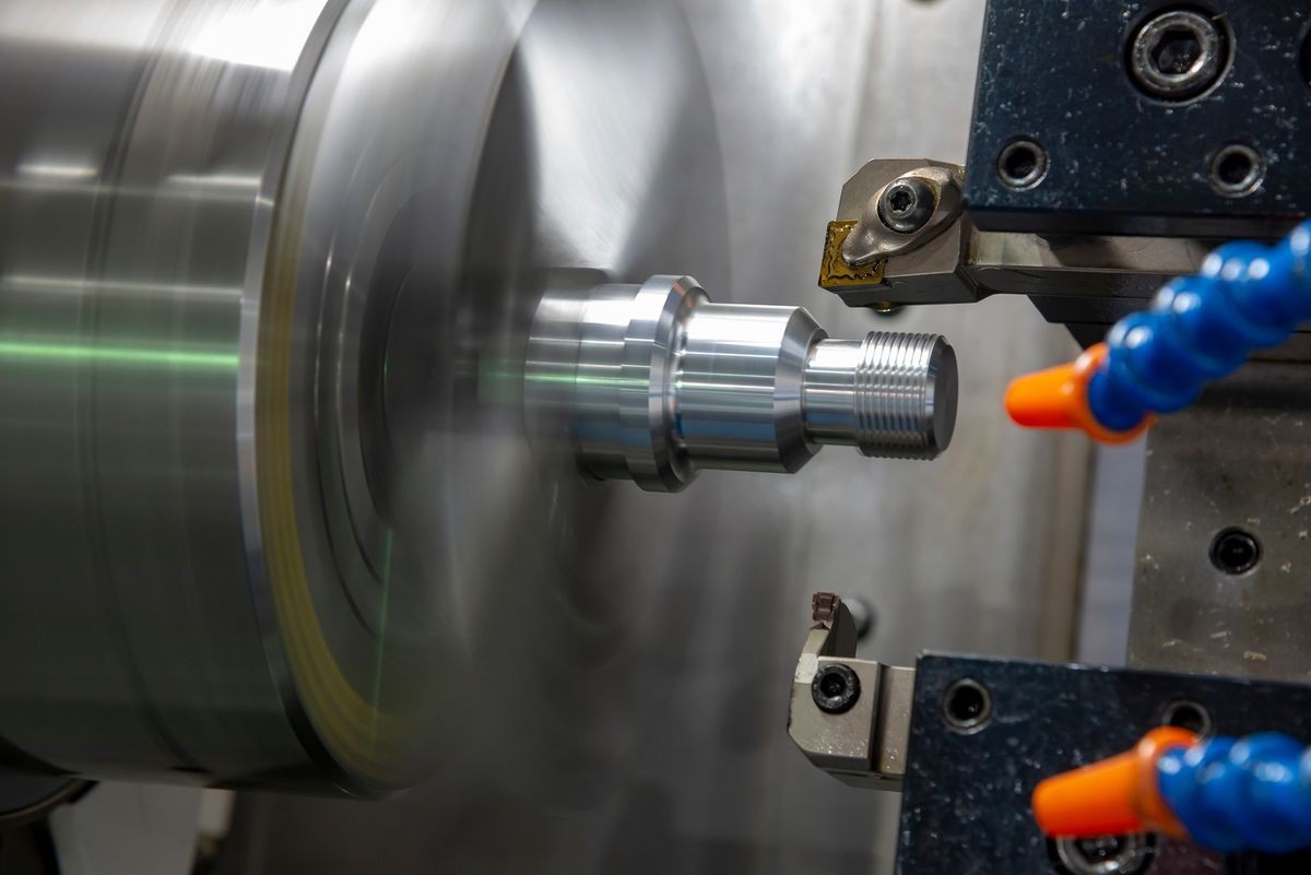 The CNC turning or lathe machine cutting the thread at the end of aluminum stud part. Modern machining concept.